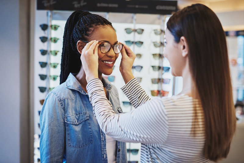 Smiling young woman being help by saleswoman.