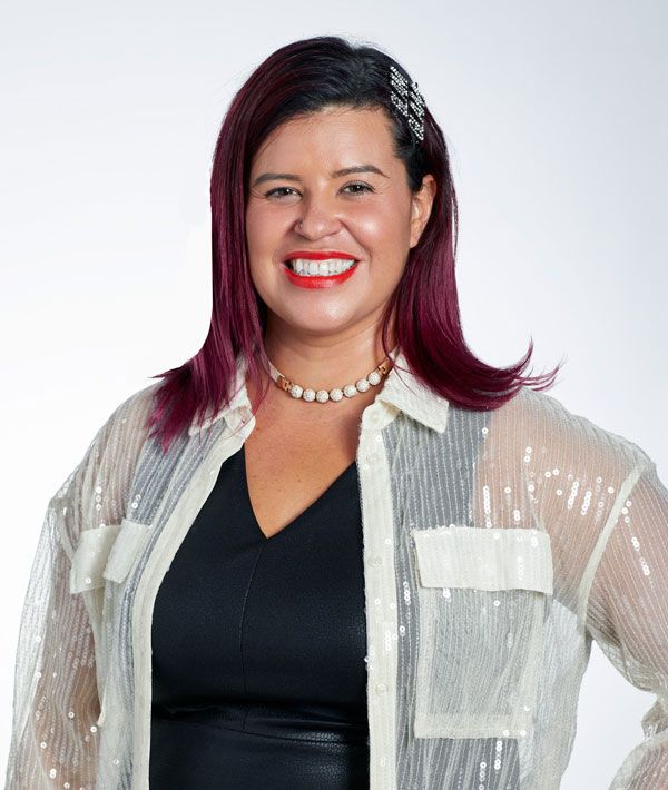 smiling woman with bright lipstick and dark hair wearing a black top with a white shiny top over it